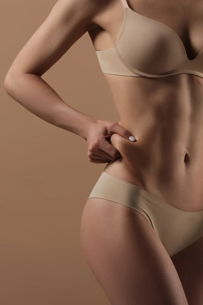 Woman pinching love handle fat before body contouring and skin tightening consultation in Lewisville TX